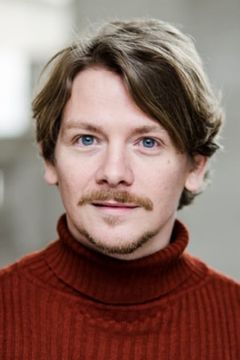 Kevin Trainor interpreta Charles Adams